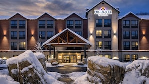 Un hôtel Microtel Wyndham doté d’une entrée couverte, entouré d’un paysage enneigé et présentant une façade bien éclairée.