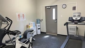 A fitness room with stationary bikes, a treadmill, and a water dispenser.