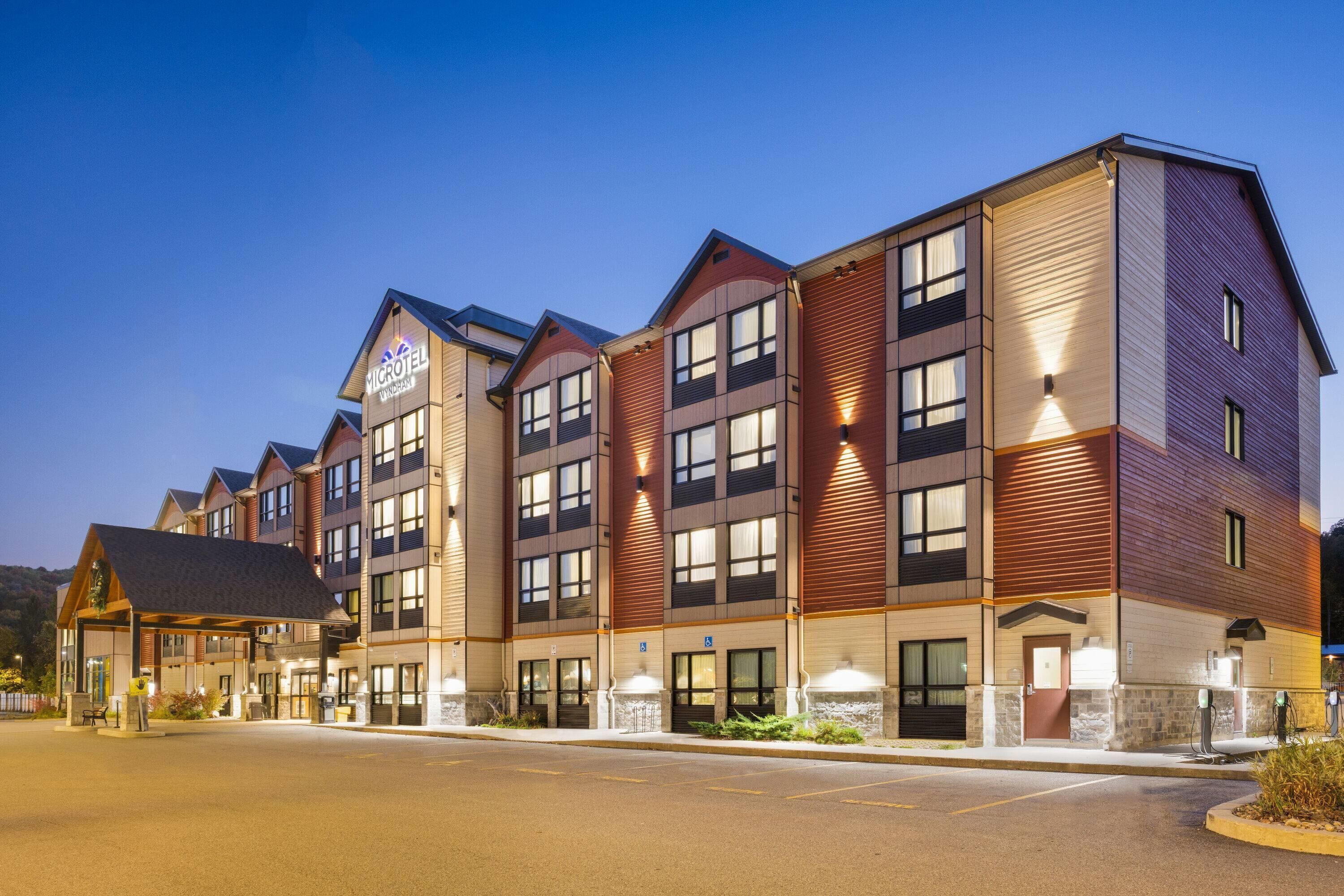 Un hôtel à plusieurs étages au design moderne, doté d’une entrée imposante avec un espace abrité et d’une enseigne indiquant qu’il s’agit d’un hôtel Microtel.