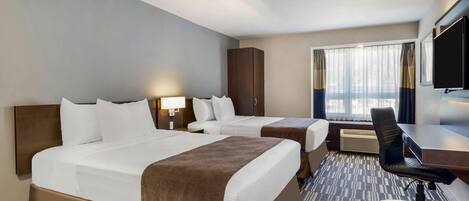 A hotel room with two beds, a desk, a chair, a TV, and a window with curtains.