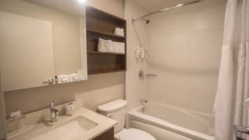 A bathroom with a sink, toilet, bathtub, and shelves with towels.