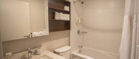 A bathroom with a sink, toilet, bathtub, and shelves with towels.