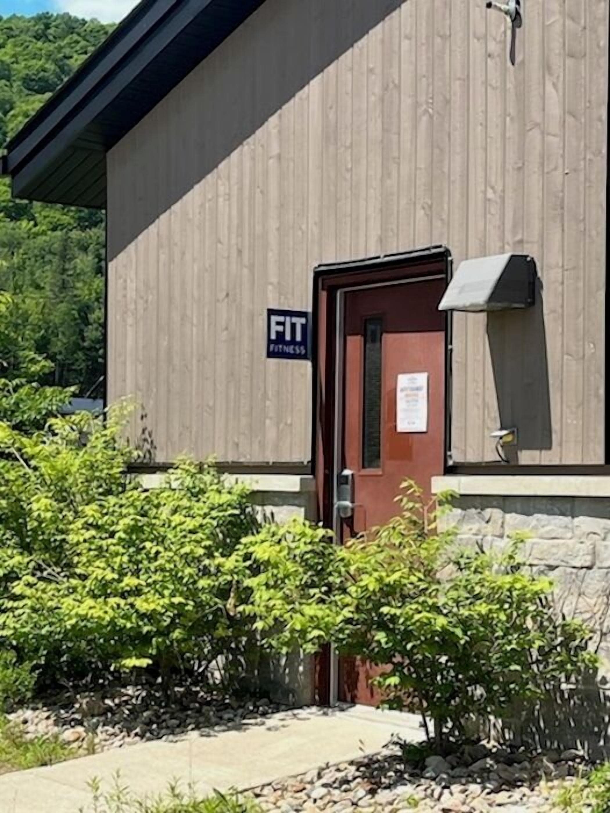 Ein Gebäude mit einem Schild, auf dem 'FIT FITNESS' steht, und einer Tür.