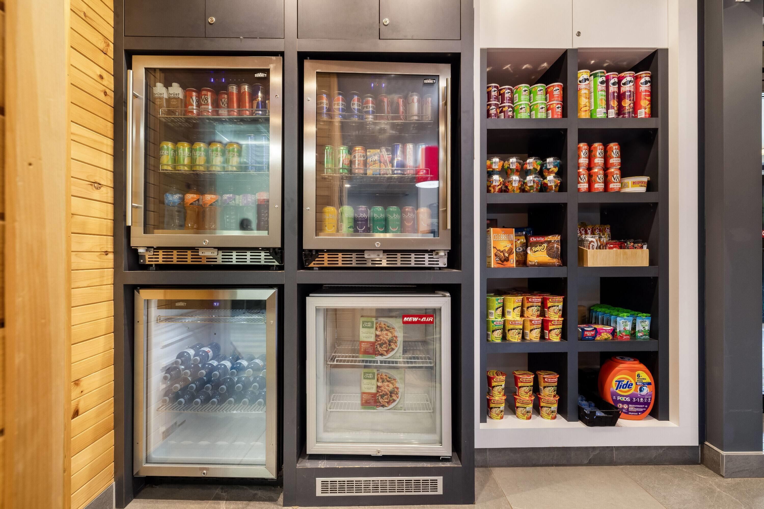 A vending machine with various beverages and snacks, a refrigerated section with bottles, and shelves stocked with canned goods and household items.