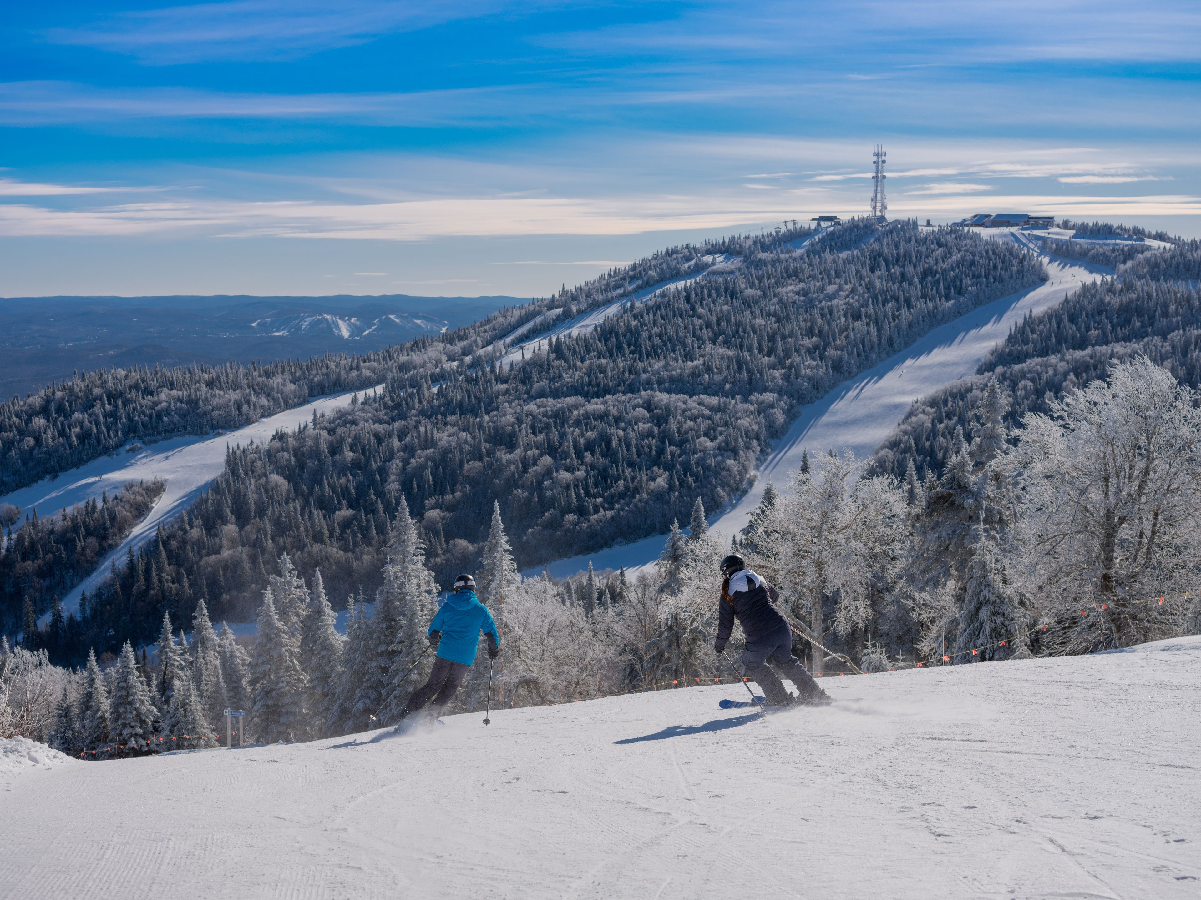 A ski slope with two skiers descending.