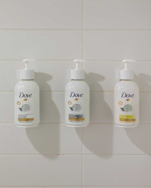 Three Dove shampoo bottles mounted on a tiled wall.