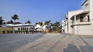 A paved courtyard with potted plants and a glass-roofed structure. - Meritas Countryside Resort - Lonavala (Mawal)