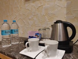 A coffee making station with Bailey water bottles, two white cups, a coffee pot, and a tea/coffee making instruction card.