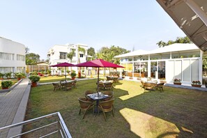 A courtyard with outdoor seating, potted plants, and a covered area with tables and chairs. - Meritas Countryside Resort - Lonavala (Mawal)
