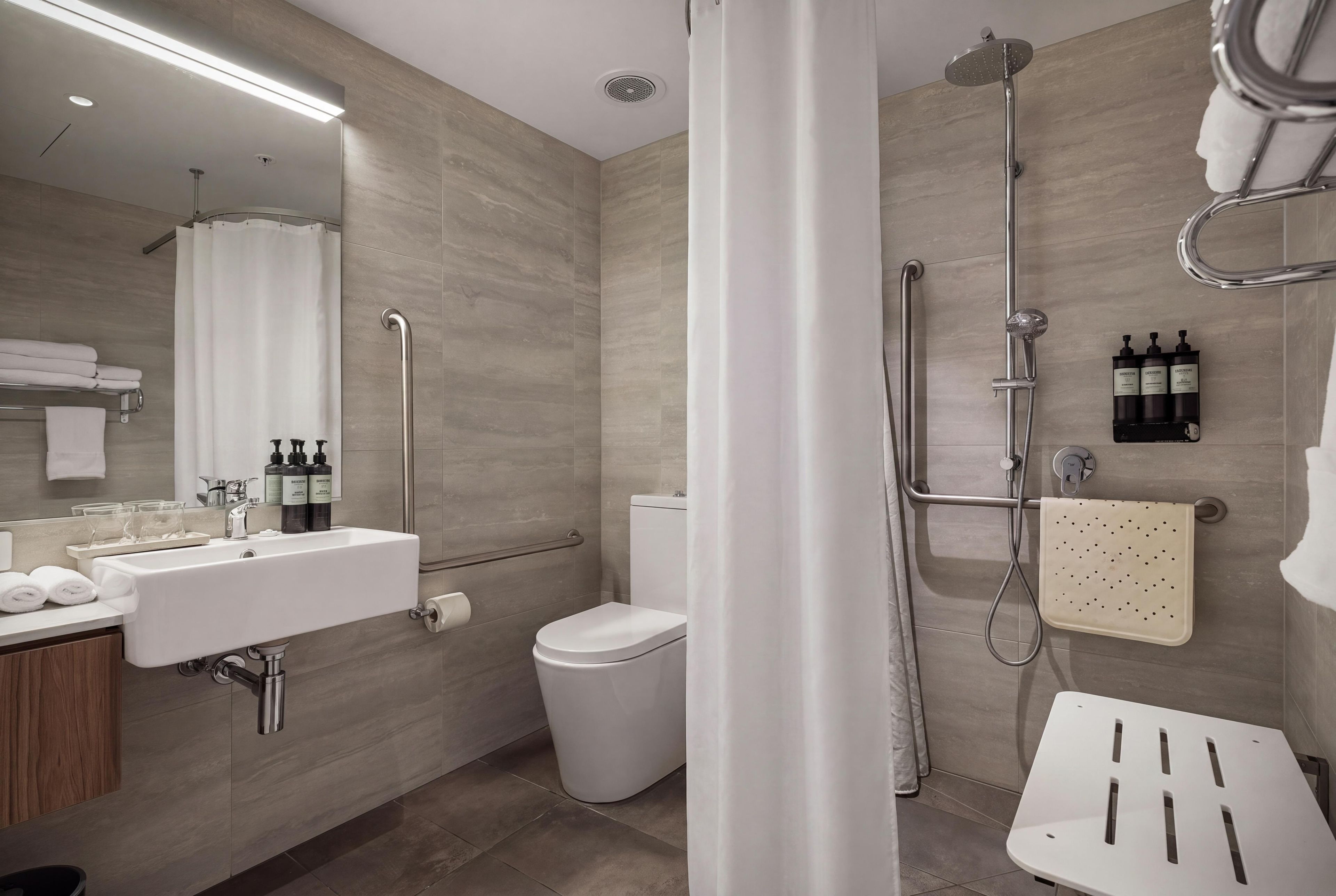 A modern bathroom with a shower, toilet, sink, and a mirror.