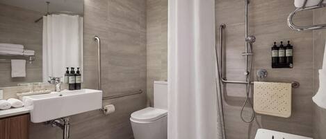 A modern bathroom with a shower, toilet, sink, and a mirror.