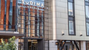 A modern hotel building with a glass facade and the name 'Sudima Hotels' prominently displayed.