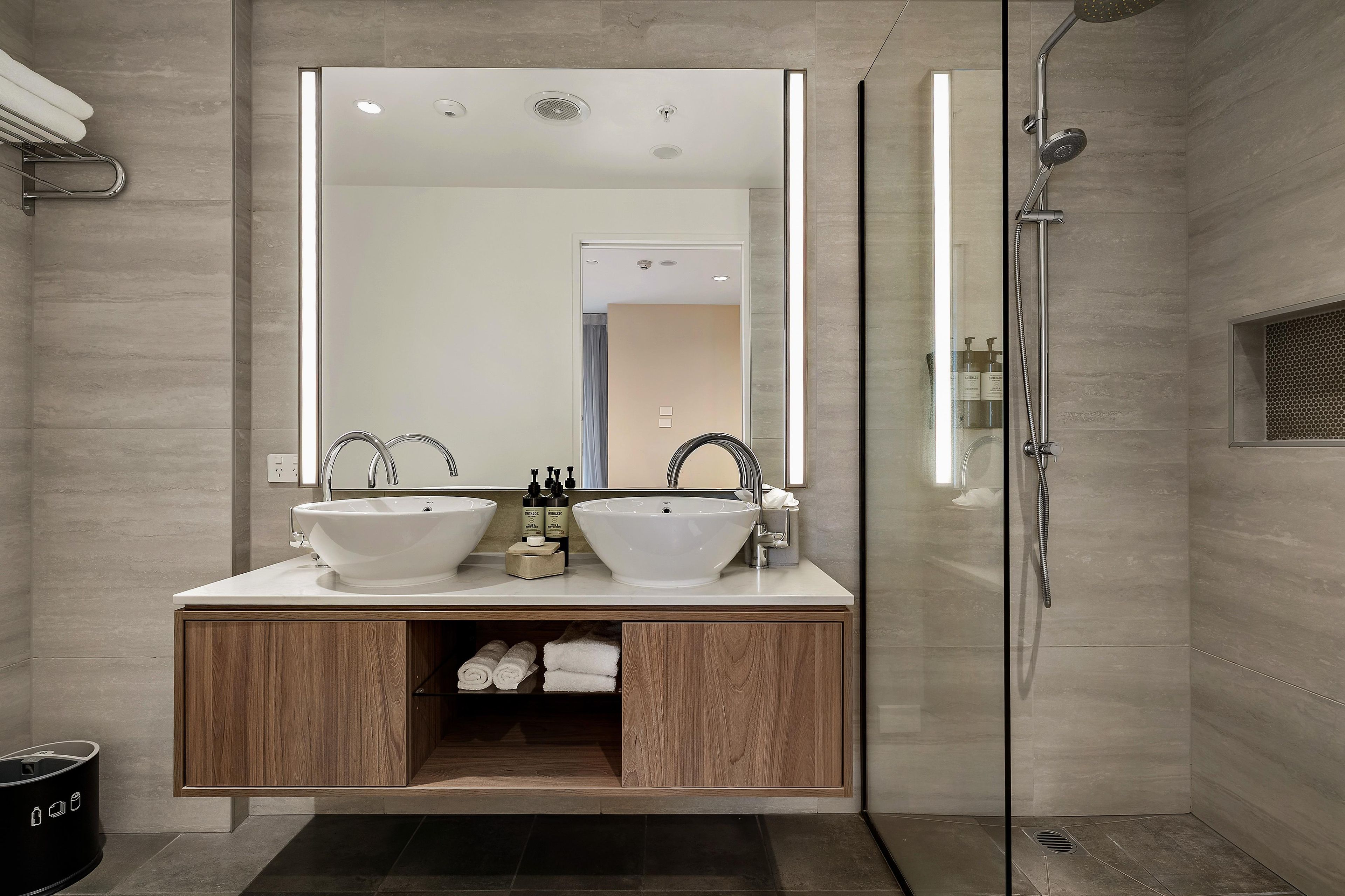 Un bagno moderno con un mobile doppio lavabo, un ampio specchio e una cabina doccia in vetro.