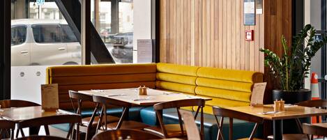 A restaurant interior with a wooden wall, yellow seating, and tables with menus.