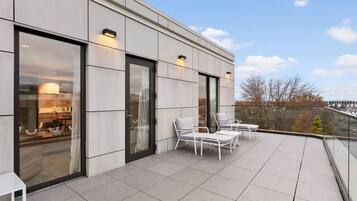 A modern building with a balcony featuring outdoor seating and large windows.