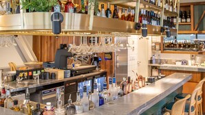 A bar area with a curved counter, multiple shelves with bottles, and bar stools. - Sudima Christchurch City (Christchurch)