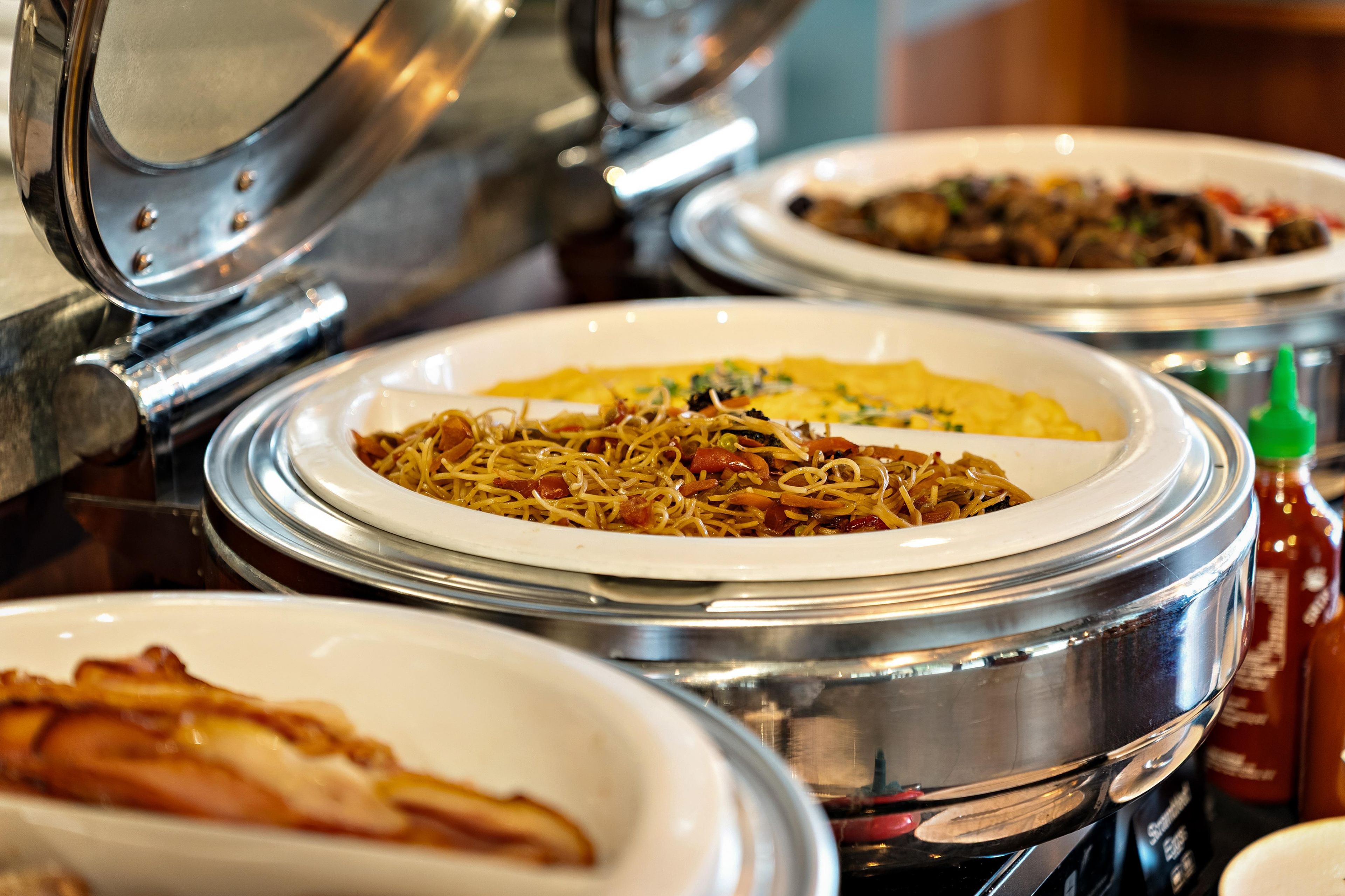 Ein Buffet mit verschiedenen Gerichten in abgedeckten Schalen.