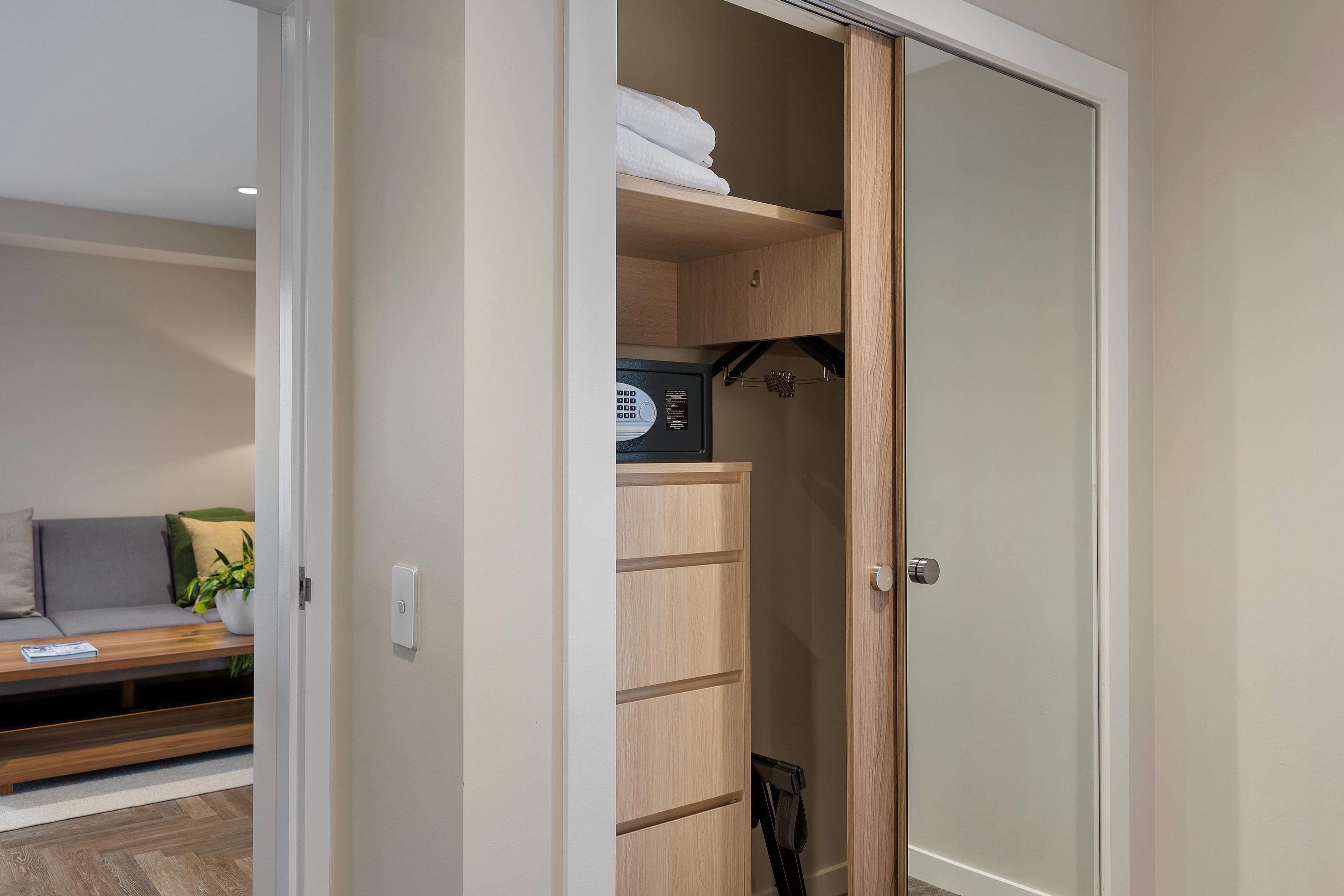 Una habitación con puerta corredera para el armario, una cama, un sofá y una mesita con una planta.