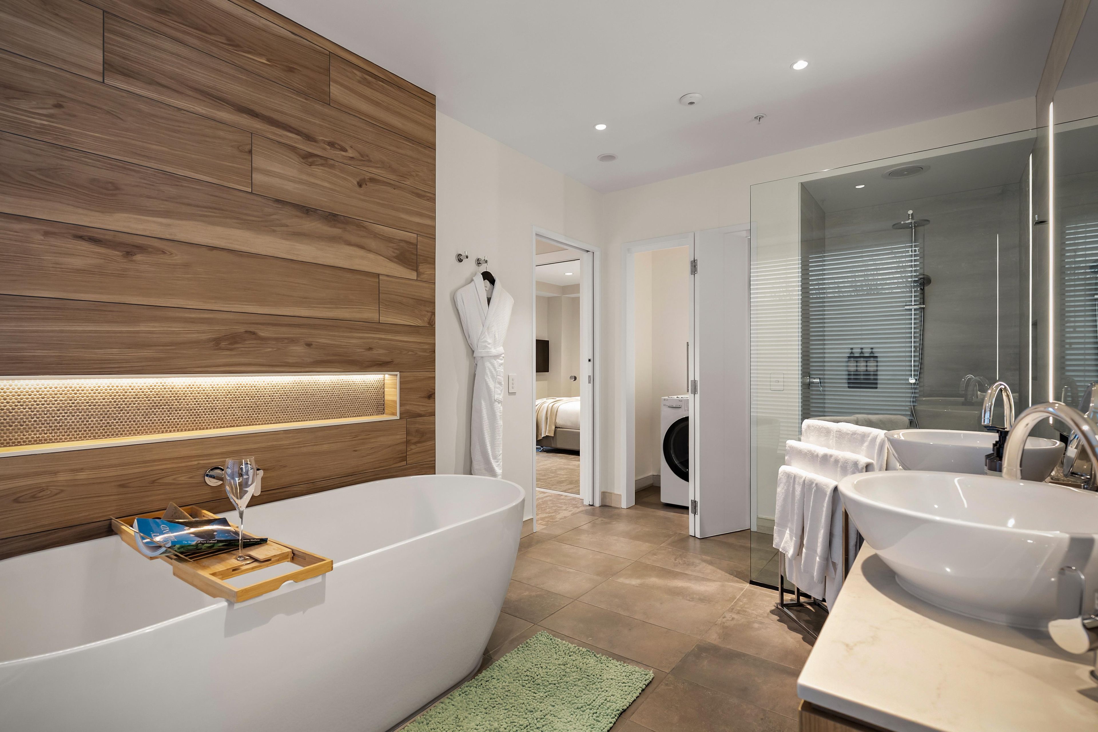 A modern bathroom with a freestanding bathtub, a glass shower enclosure, and a vanity with two sinks.