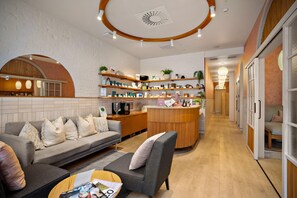 A modern interior with a sofa, coffee table, and a kitchen area with shelves and appliances. - Sudima Christchurch City (Christchurch)
