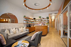 Um interior moderno com sofá, mesa de centro e área de cozinha com prateleiras e eletrodomésticos.