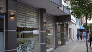 La façade d’un hôtel, dotée de grandes fenêtres, d’un espace salon bien visible avec des chaises, et d’une enseigne indiquant si l’hôtel a des chambres disponibles.