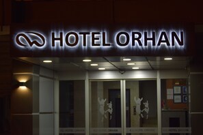 A hotel entrance with illuminated signage reading "HOTEL ORHAN" and decorative glass panels. - Otel Orhan (Aydin)
