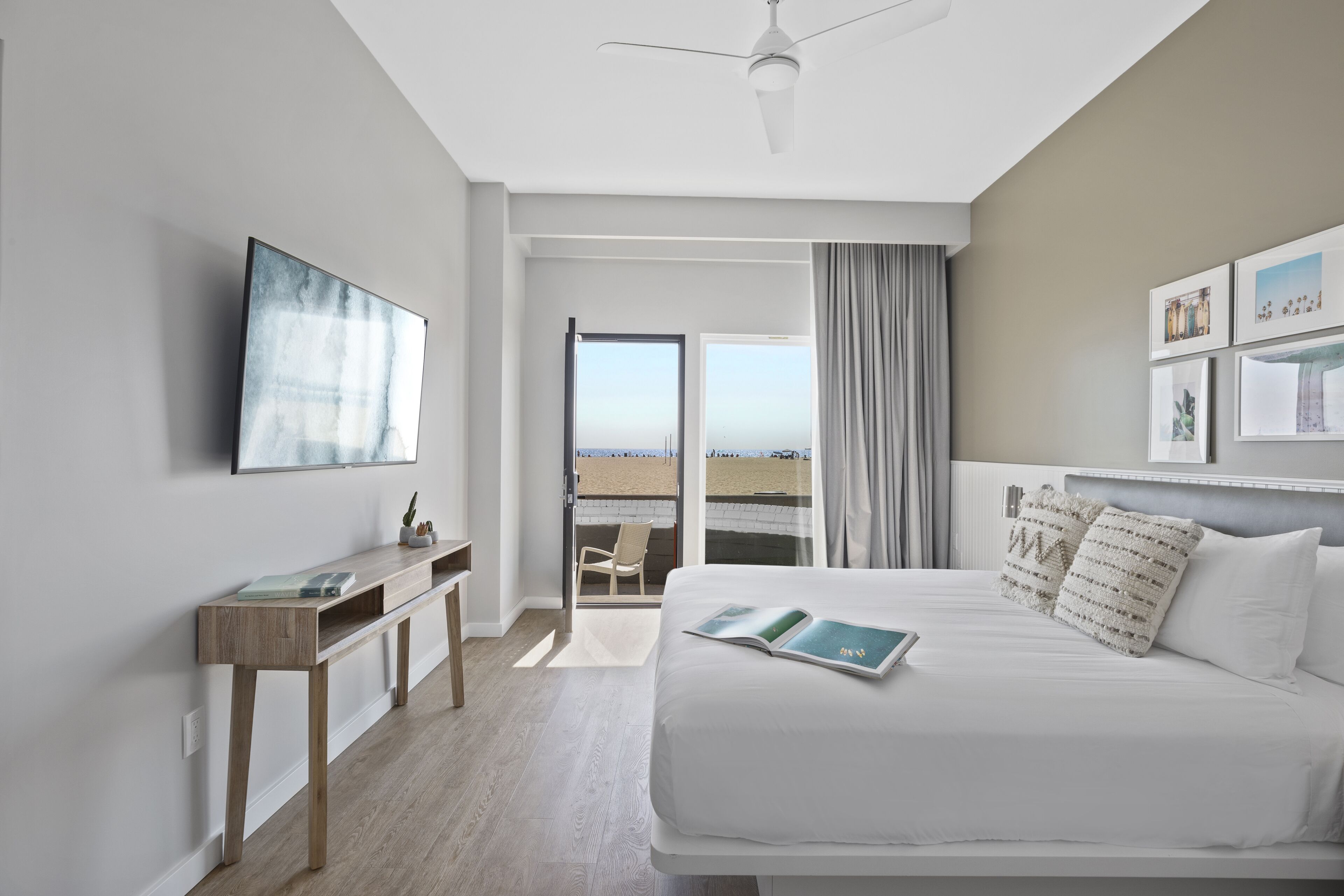 Une chambre d’hôtel moderne avec un lit, un bureau et une vue sur la plage.