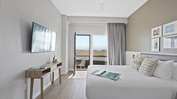 Une chambre d’hôtel moderne avec un lit, un bureau et une vue sur la plage.