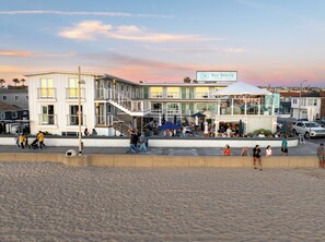 A beachfront building with a sign reading 'Sea Sprite Beach Club,' featuring a multi-level structure with outdoor seating and a covered area. - Sea Sprite Beach Club (Hermosa Beach)