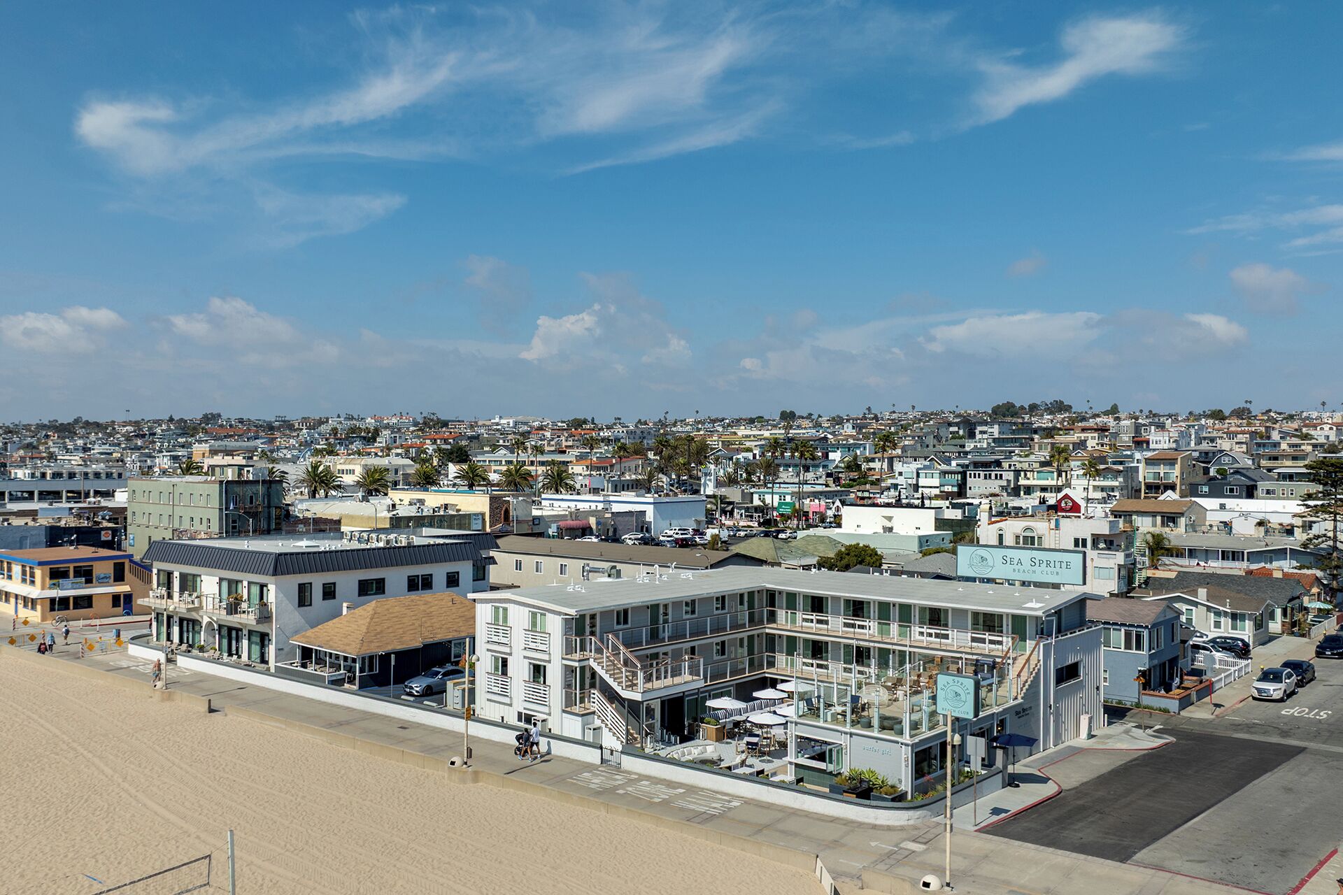 A coastal building with a beach view, multiple floors, and a sign for 'Sea Sprite Beach Club'.