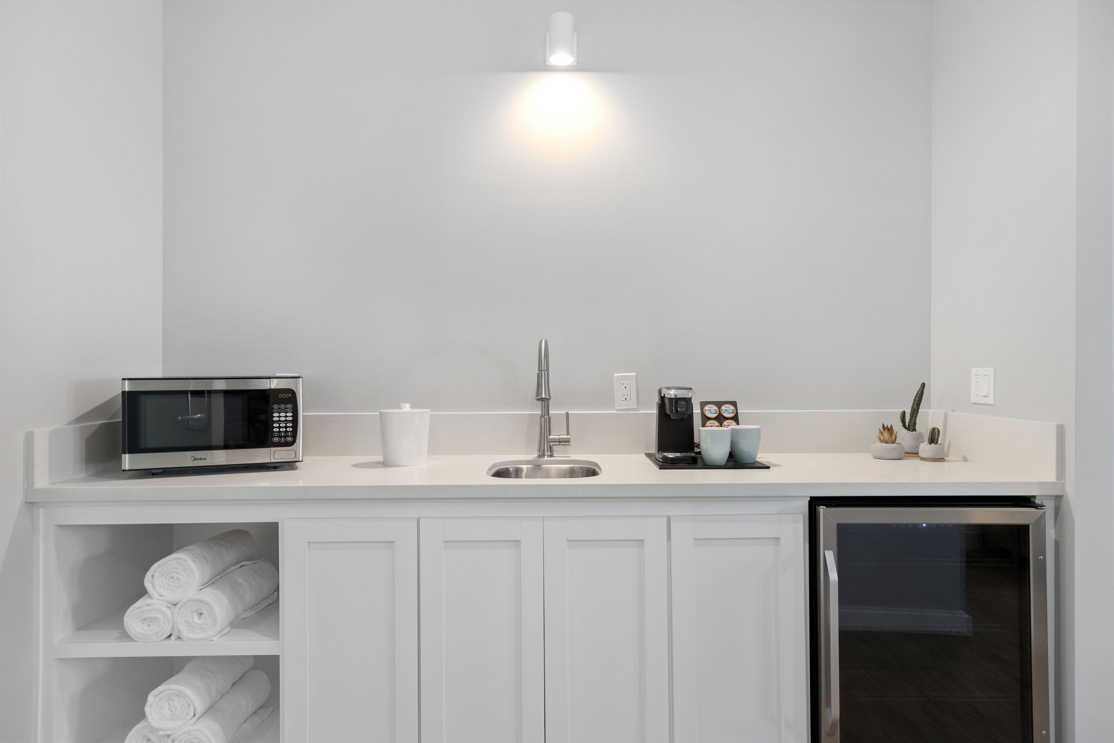 A modern kitchen with a built-in microwave, coffee maker, and a refrigerator.