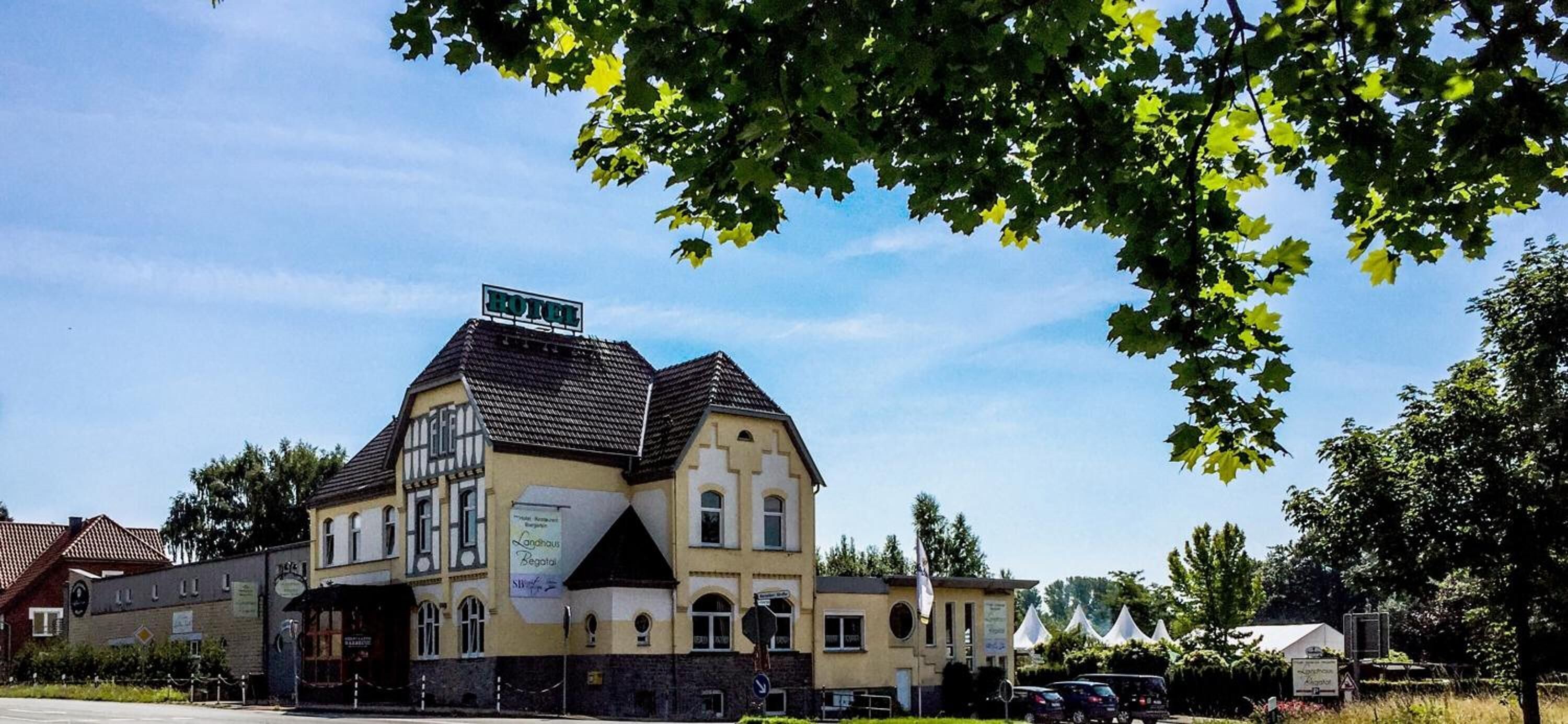 Ein zweistöckiges Gebäude mit einem Schild, das es als Hotel kennzeichnet. Das Gebäude hat einen traditionellen Baustil mit einem Satteldach und einem Balkon im zweiten Obergeschoss.