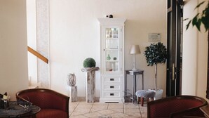 A room with a dining table, two red upholstered chairs, a white cabinet, a small potted plant, and a lamp. - Landhaus Begatal (Doerentrup)