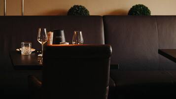 Un comedor con una mesa dispuesta para dos personas, una fotografía en blanco y negro enmarcada en la pared, y un sofá de cuero marrón oscuro.