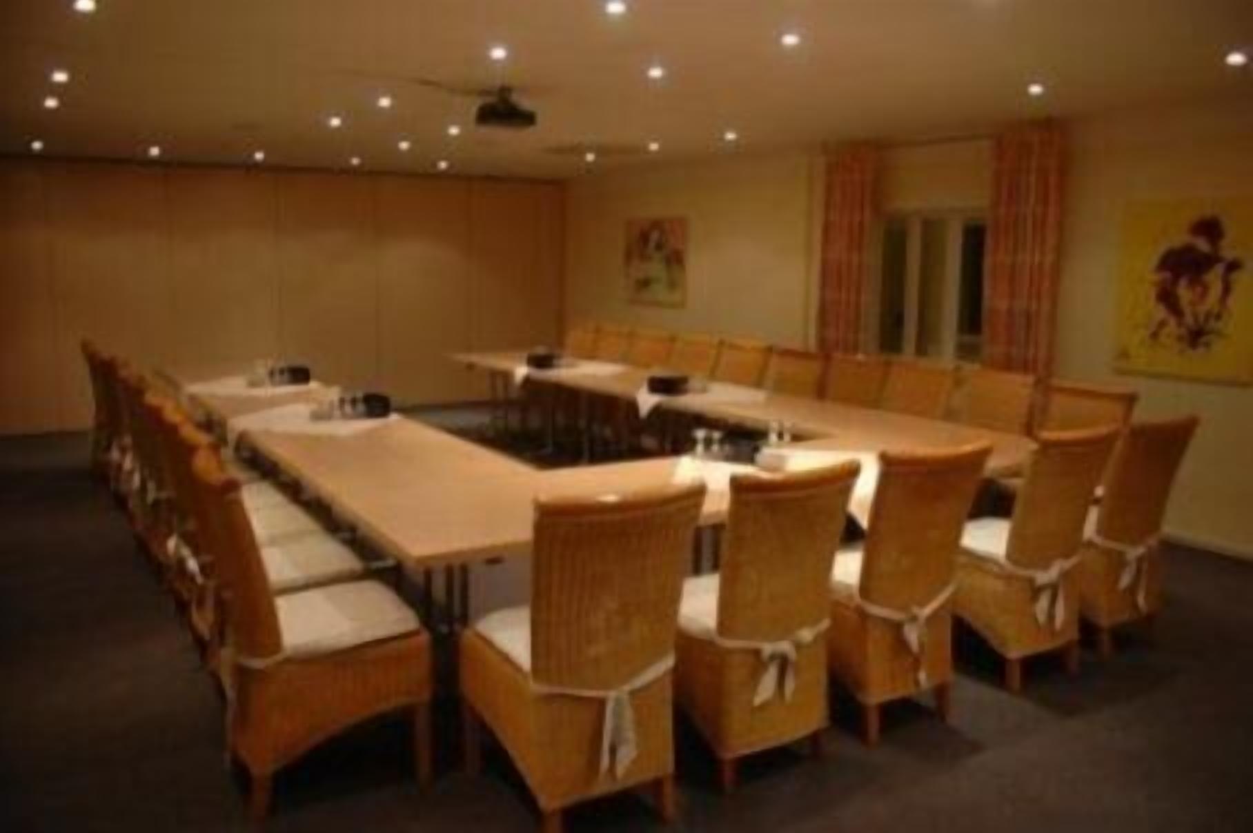 A conference room with a long table and chairs, a ceiling fan, and a poster on the wall.