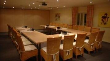 A conference room with a long table and chairs, a ceiling fan, and a poster on the wall.