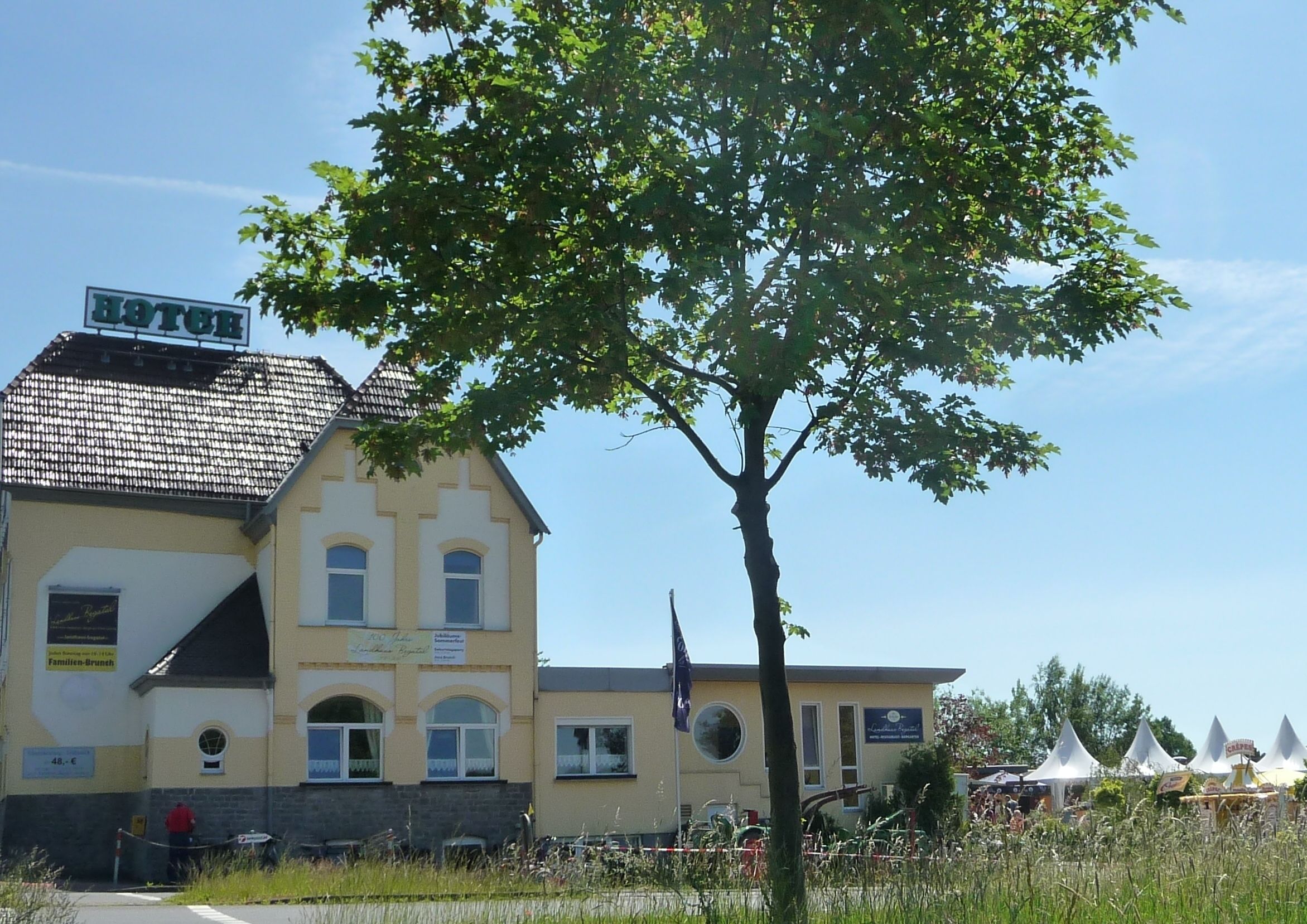 A hotel with a traditional architectural style, featuring a tiled roof and a signboard.