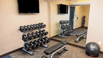 A gym with dumbbells, a bench, and a ball.