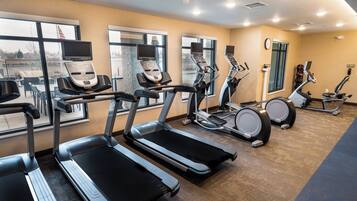 Une salle de sport équipée de tapis de course, d’appareils elliptiques et de vélos d’exercice.