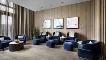 A modern lounge area with blue armchairs, a round coffee table, and artwork on the wall.
