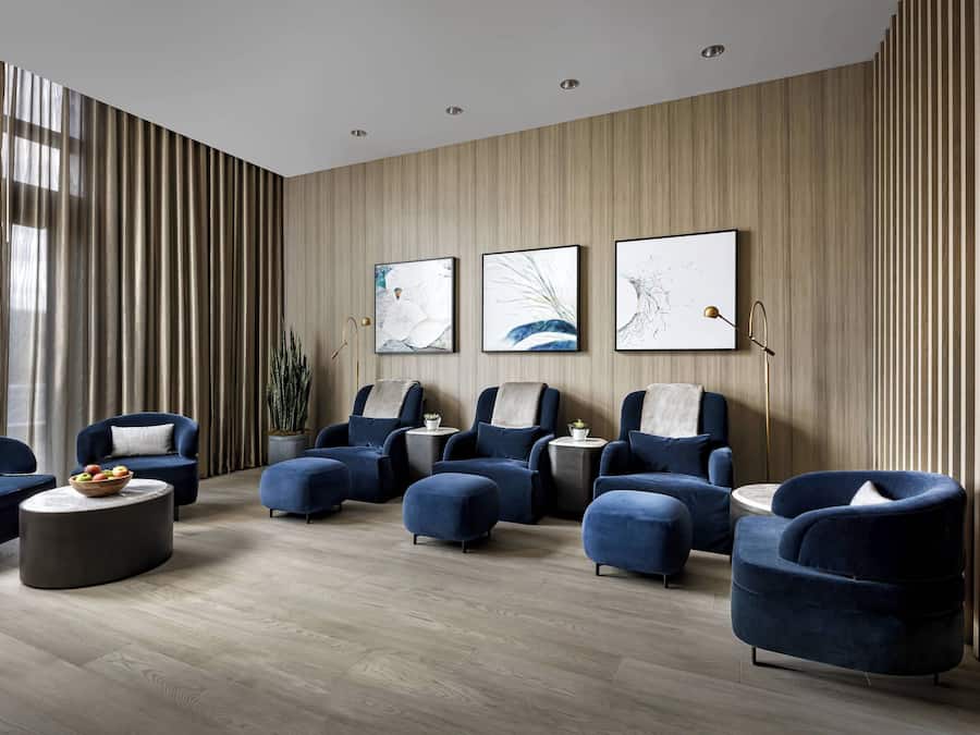 A modern lounge area with blue armchairs, a round coffee table, and artwork on the wall.