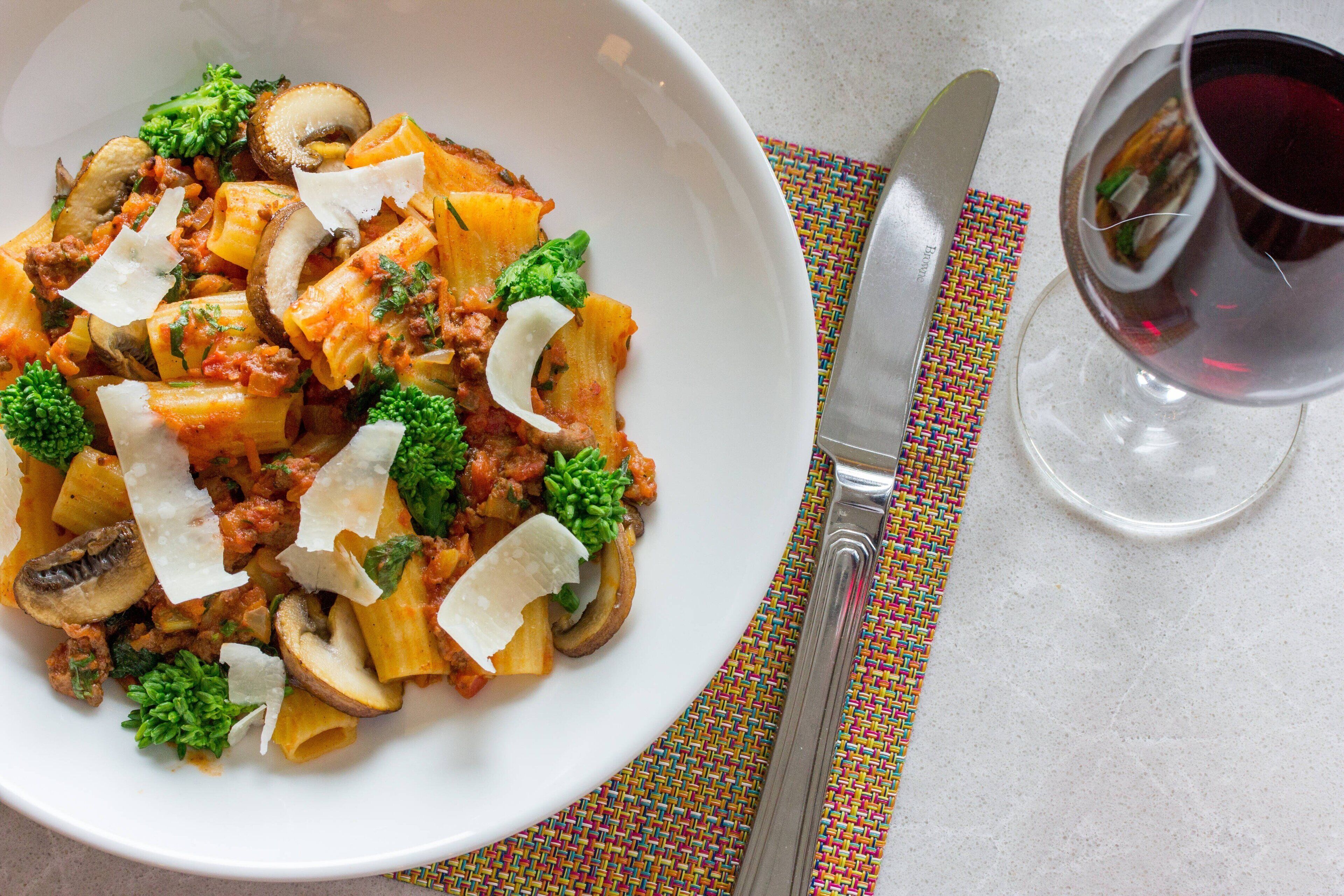 Een bord pasta met champignons, broccoli en kaas.