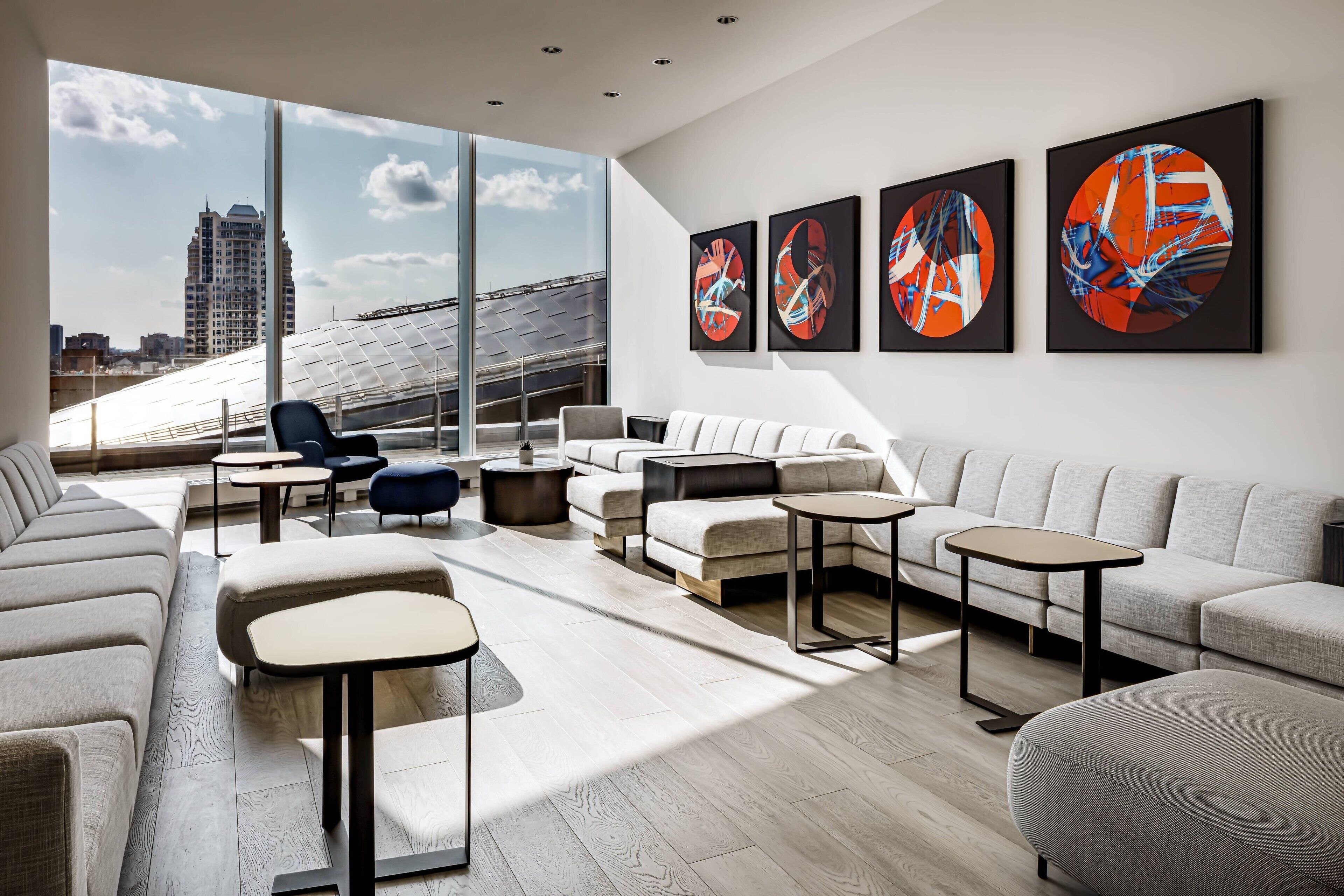 Un salón moderno con un gran ventanal, un sofá, una mesa de centro y arte abstracto en la pared.