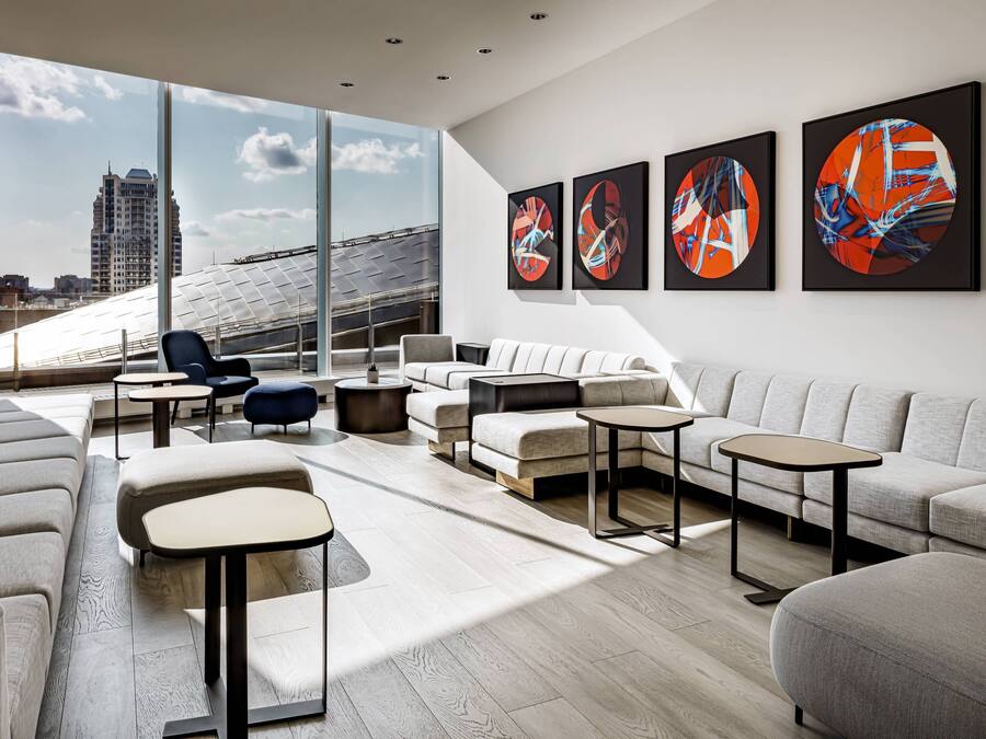 Un salón moderno con un gran ventanal, un sofá, una mesa de centro y arte abstracto en la pared.