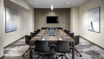 A conference room with a long table, chairs, a flat-screen TV, and artwork on the walls.