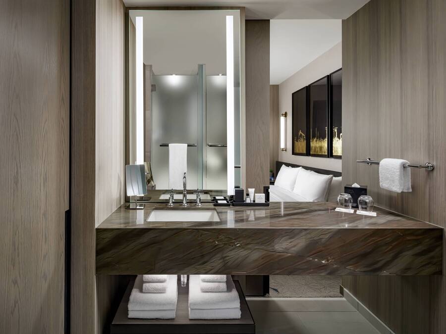 Een moderne badkamer met een marmeren aanrechtblad, twee wastafels, een grote spiegel en een handdoekrek.