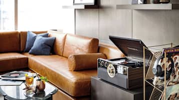 A modern living room with a leather sofa, a glass coffee table with a drink and a plant, and a vintage turntable on a cabinet.