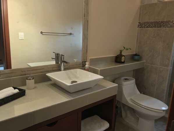 Um banheiro com pia branca, vaso sanitário e espelho.