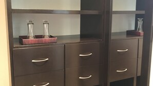 A dark wooden cabinet with multiple drawers and shelves, some containing glass bottles. - YurInn (Cancun)
